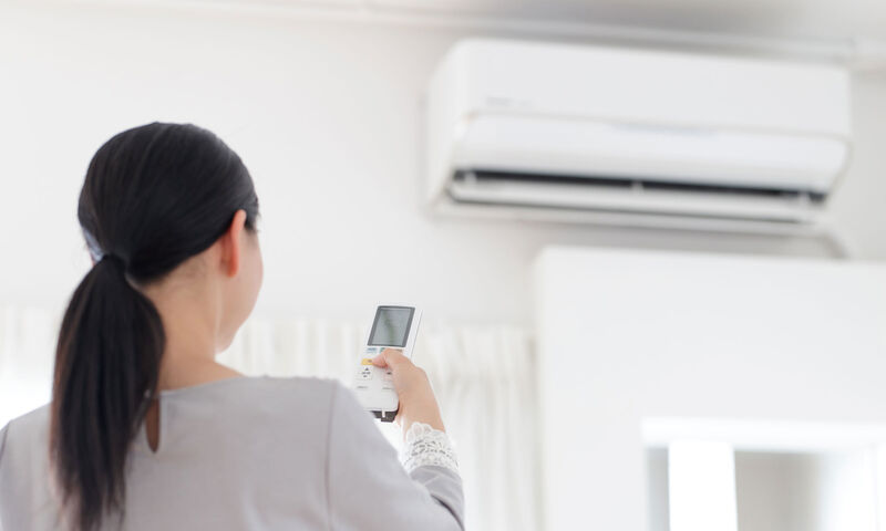 Femme utilisant une télécommande de climatisation